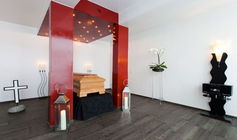 Ein Raum mit einem Holzsarg unter einem roten Baldachin