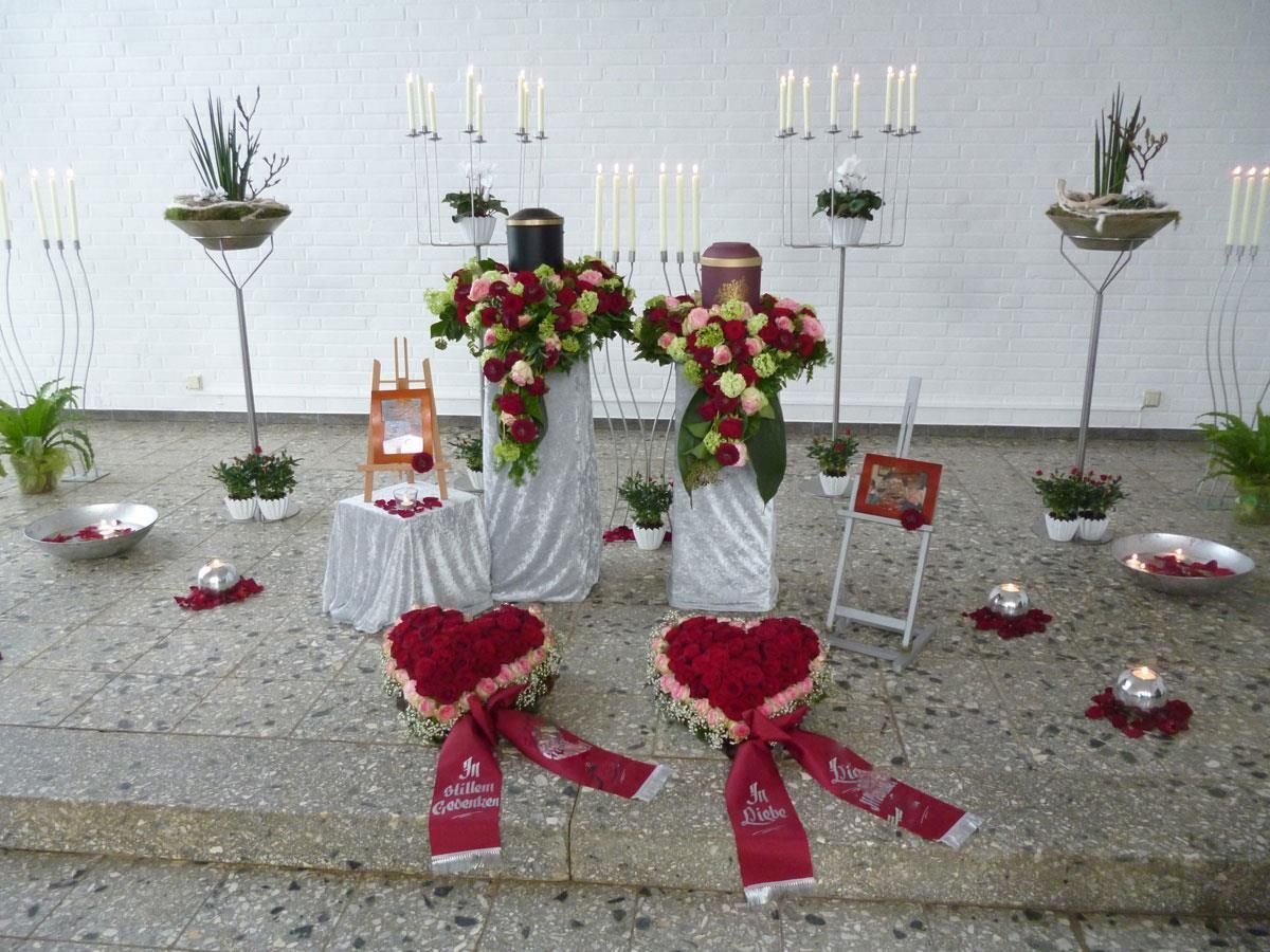 Eine Anordnung von Blumen und Kerzen mit zwei Herzen auf dem Boden