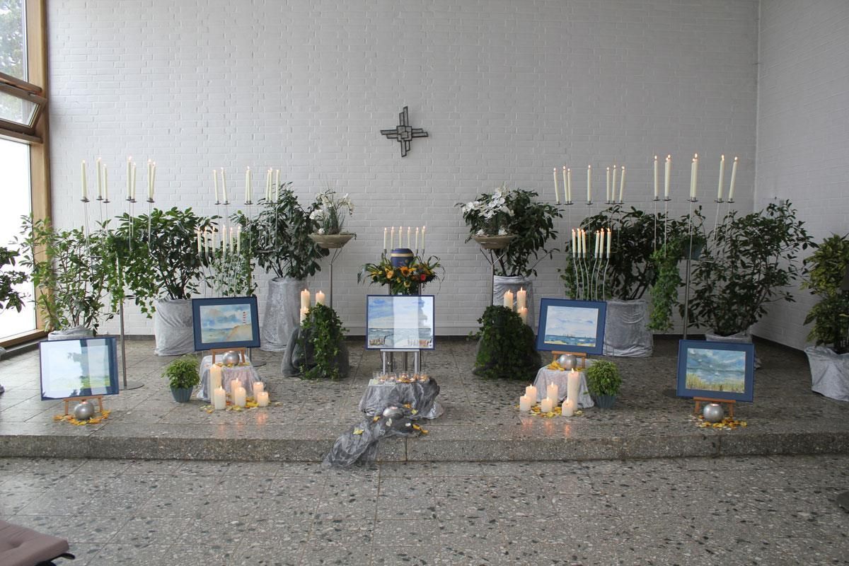 Eine Ausstellung von Blumen und Kerzen in einem Raum mit einem Kreuz an der Wand