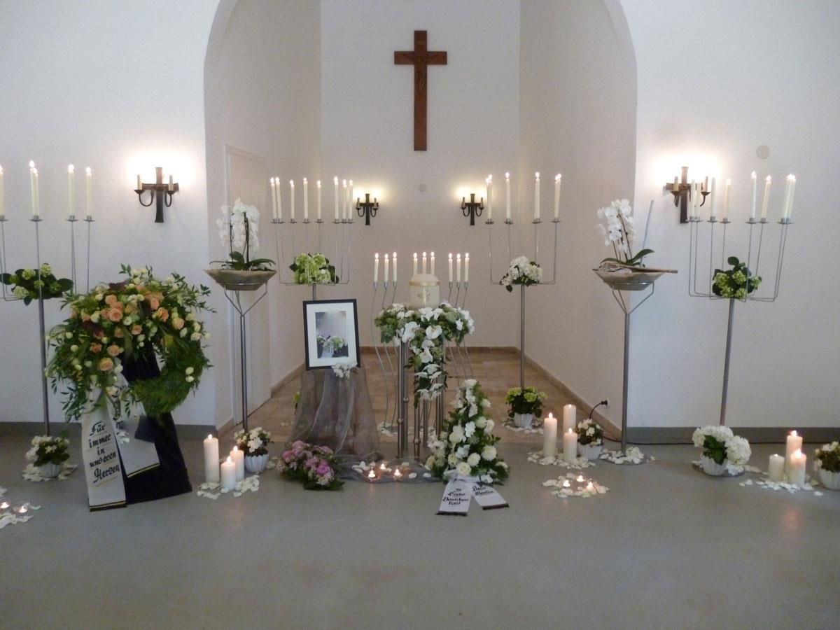 Eine Kirche mit Blumen und Kerzen und einem Kreuz an der Wand