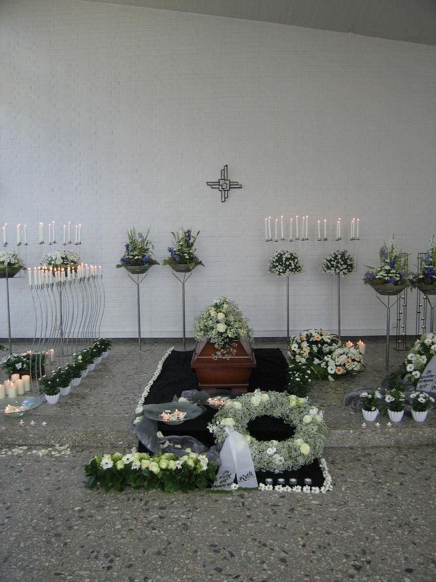 Ein Raum mit Blumen und Kerzen und einem Kreuz an der Wand