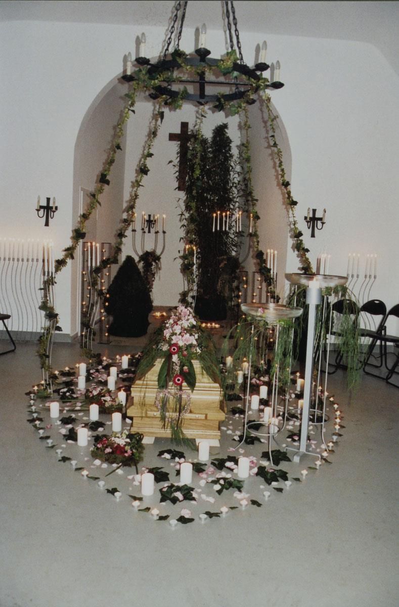Ein Sarg ist in einer Kirche von Kerzen und Blumen umgeben