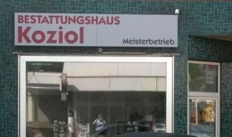 A store front with a sign that says ' bestattungshaus koziol meisterbetrieb ' on it.