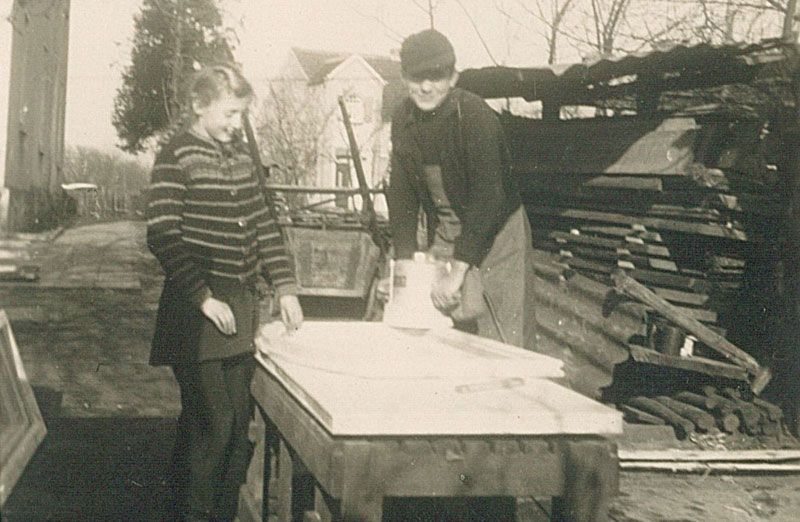 Ein Schwarzweißfoto von zwei Männern, die um einen Tisch herumstehen