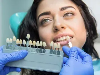 Una mujer está sentada en una silla dental mientras un dentista le examina los dientes.