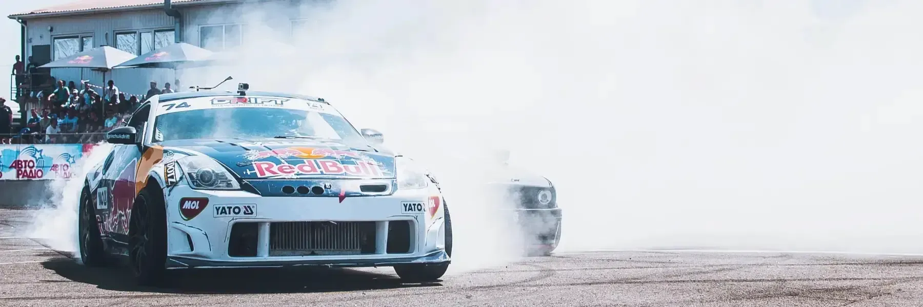 Un coche de carreras de Red Bull derrapa en un circuito, creando una gran nube de humo blanco de los neumáticos