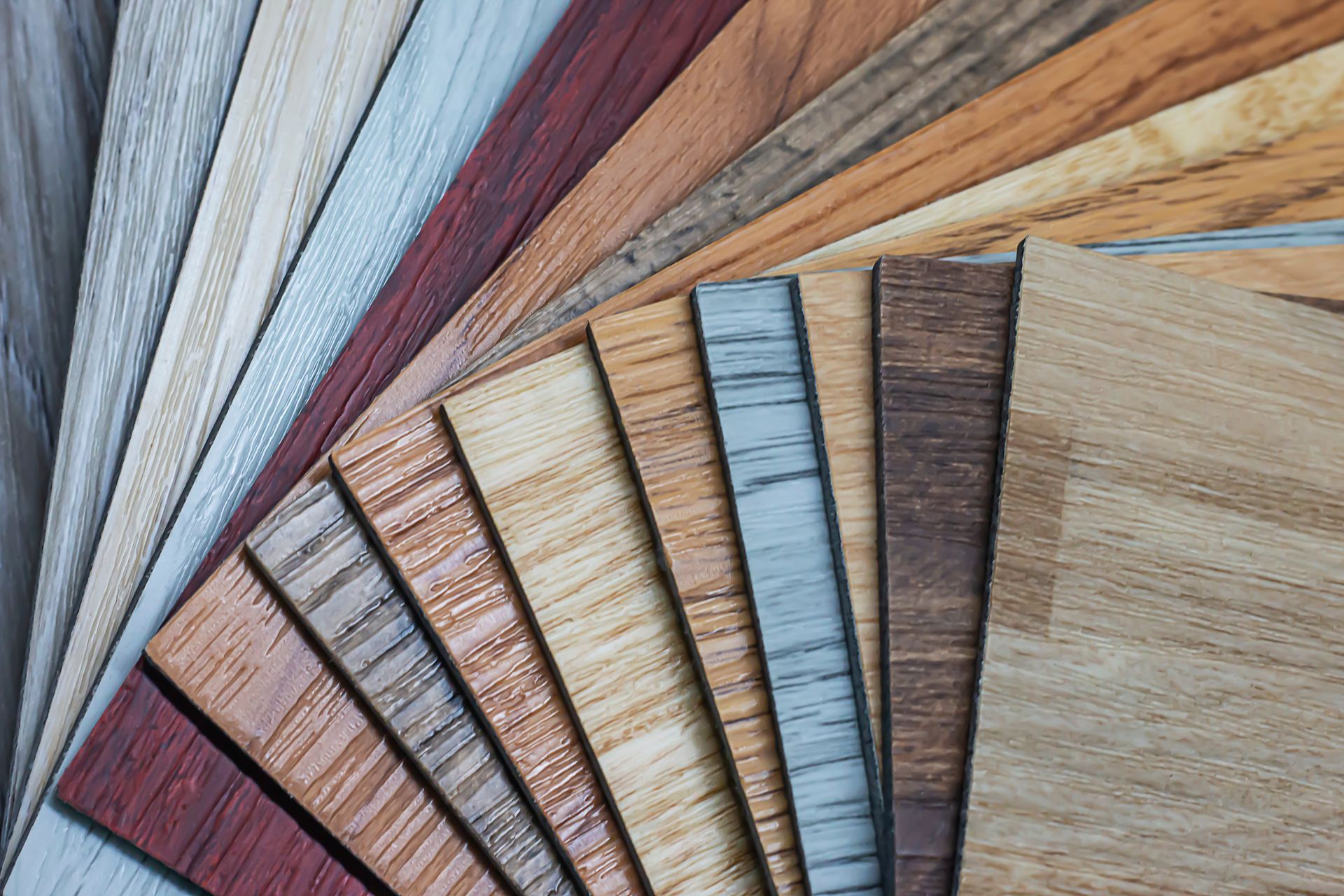 Échantillons de lames de parquet et de stratifié disposées en éventail dans diverses teintes et textures naturelles.