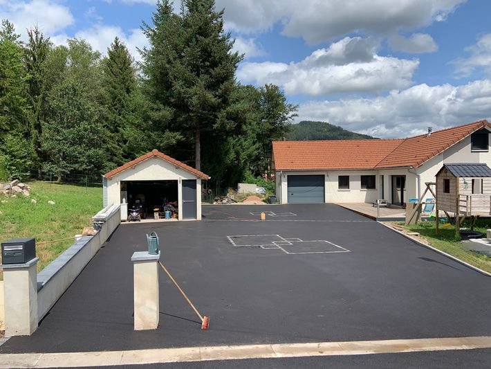 Allée en asphalte à côté d’une maison et d’un garage indépendant.