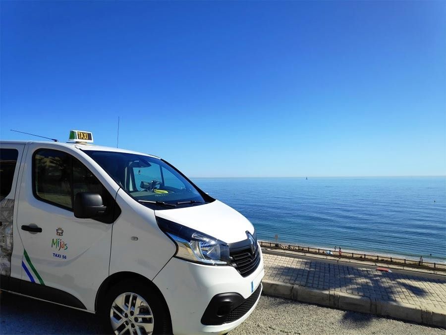 Una camioneta blanca está estacionada al costado de la carretera al lado del océano.