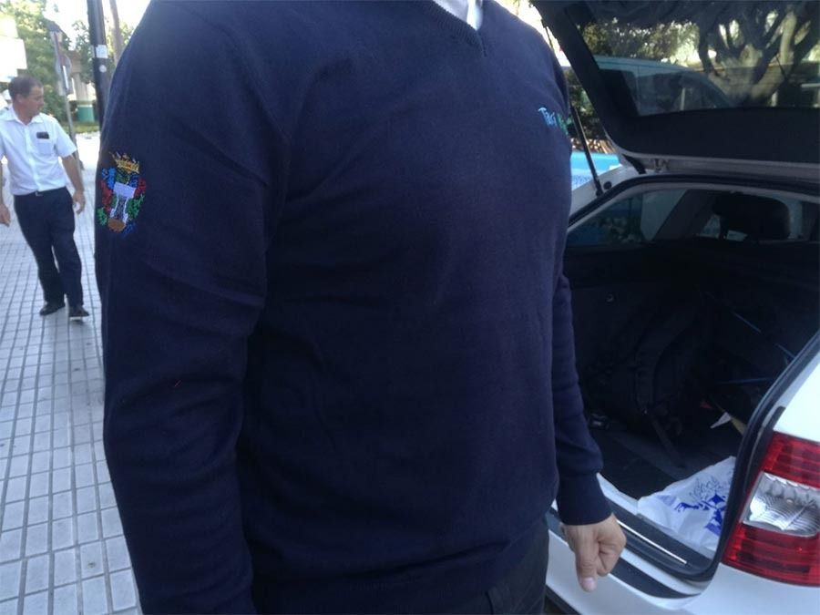 Un hombre de pie junto a un coche con el maletero abierto.