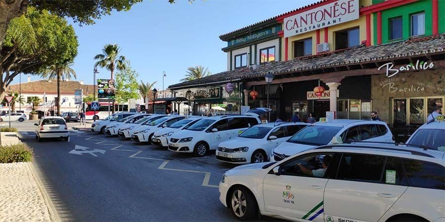 Una fila de taxis están estacionados frente a un edificio.