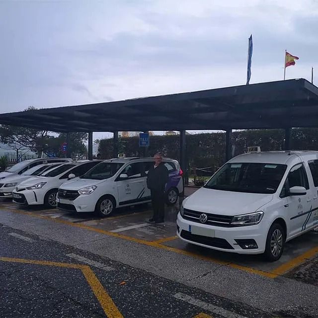 Una fila de coches blancos están aparcados bajo un dosel.