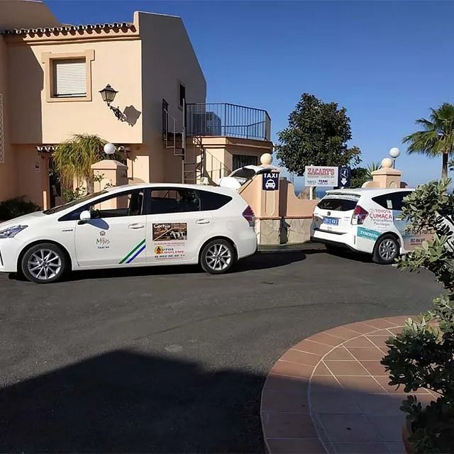 Dos coches están aparcados delante de un edificio con un cartel que dice 'alquiler'.