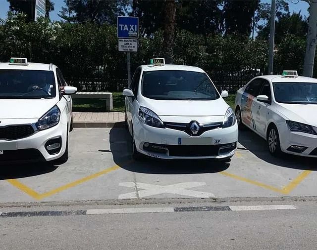 Tres taxis blancos están estacionados uno al lado del otro en un estacionamiento.