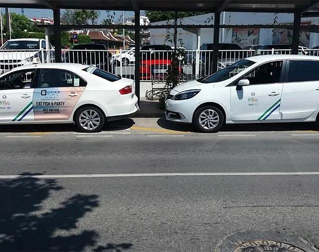 Dos coches blancos están aparcados uno al lado del otro al costado de la carretera.