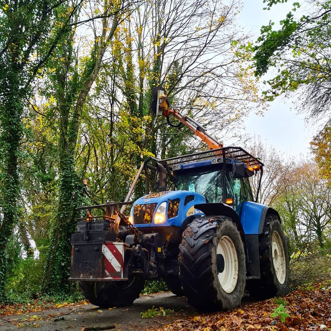 tracteur bleu qui fait élagage des arbres vu de profil