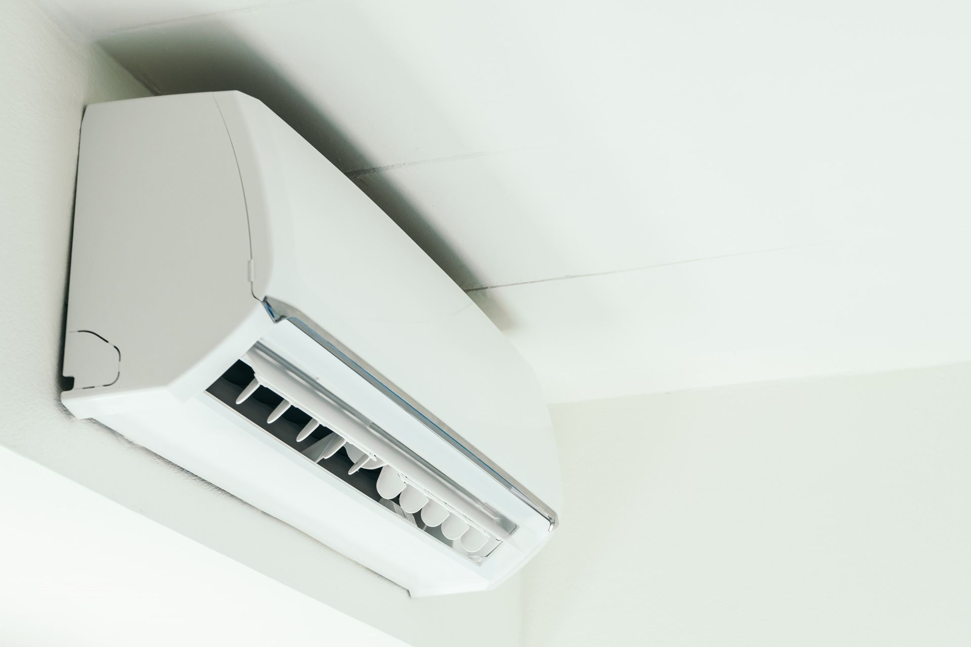 Unidad de aire acondicionado de pared de color blanco sobre una pared blanca.