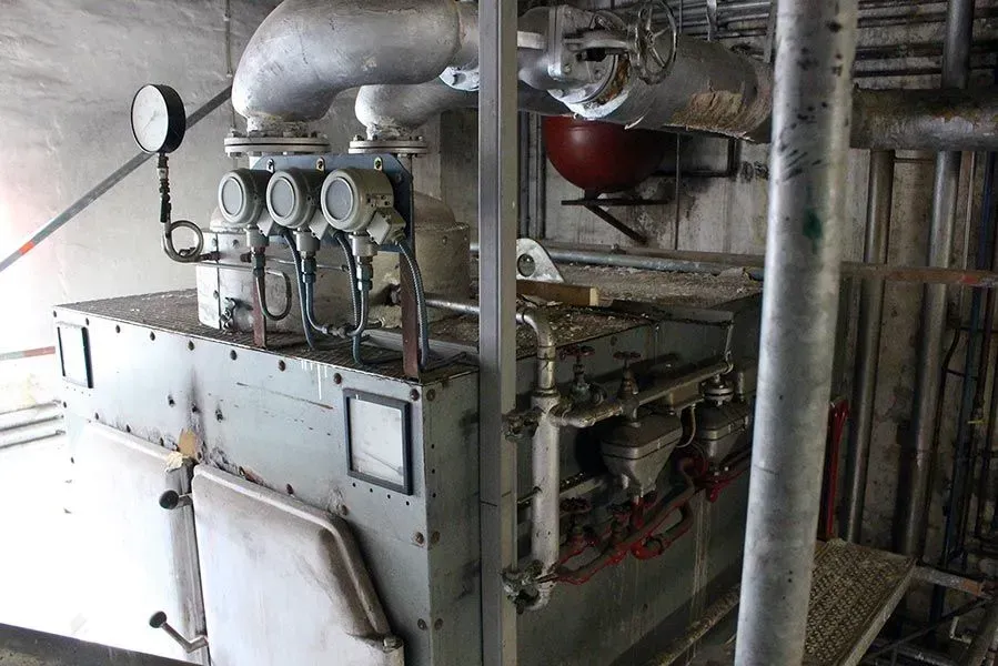 Ein großer Industriekessel oder eine Heizanlage mit Metallrohren, Manometern und elektrischen Bauteilen in einer Fabrik.