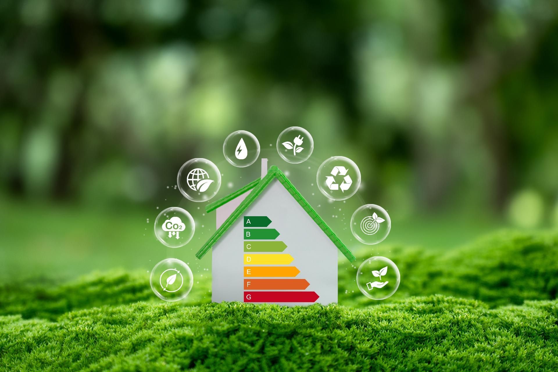 Ein Miniaturhaus auf grünem Moos, mit einem Energieeffizienz-Etikett, umgeben von schwebenden, umweltfreundlichen Symbolen.