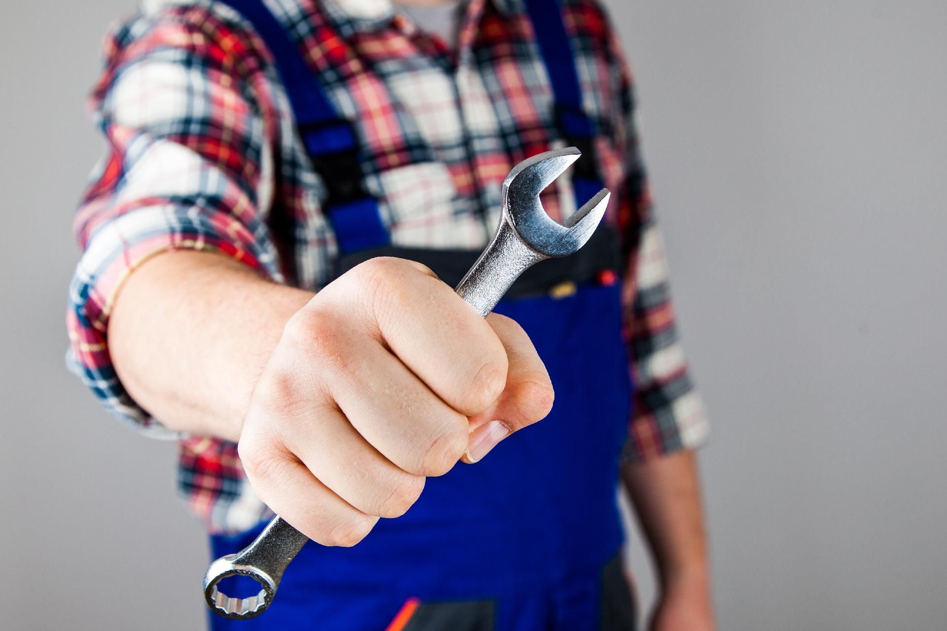 Nahaufnahme einer Person, die einen Schraubenschlüssel in der Hand hält