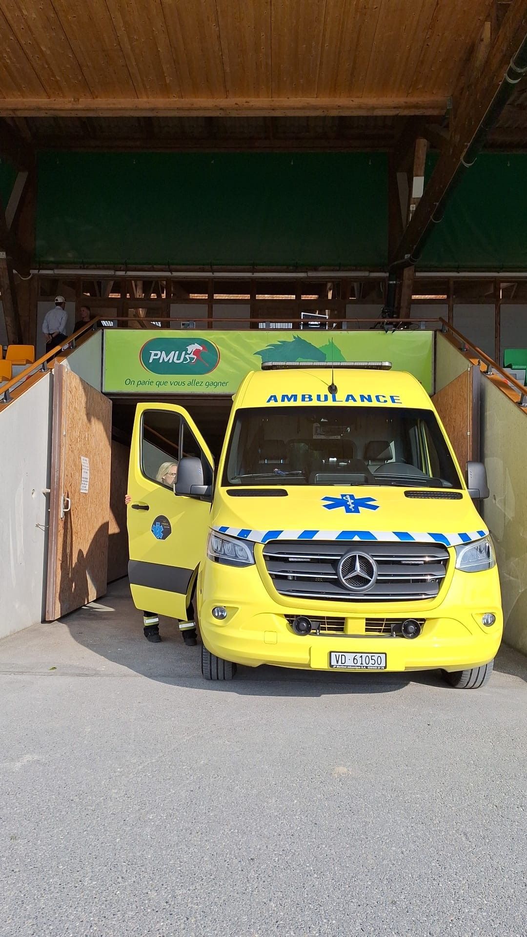 Une ambulance jaune est garée devant un bâtiment avec ses portes ouvertes.