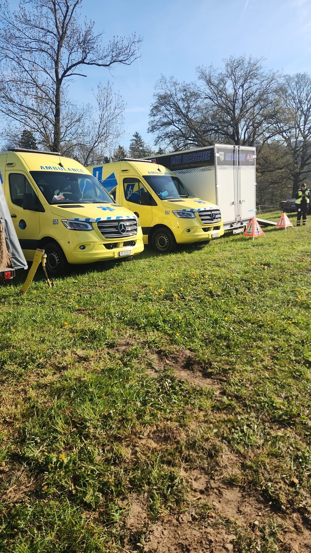 Trois fourgons d'ambulance sont garés dans un champ herbeux.