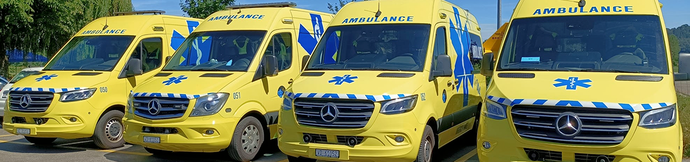 Une rangée de fourgons ambulanciers jaunes garés les uns à côté des autres.