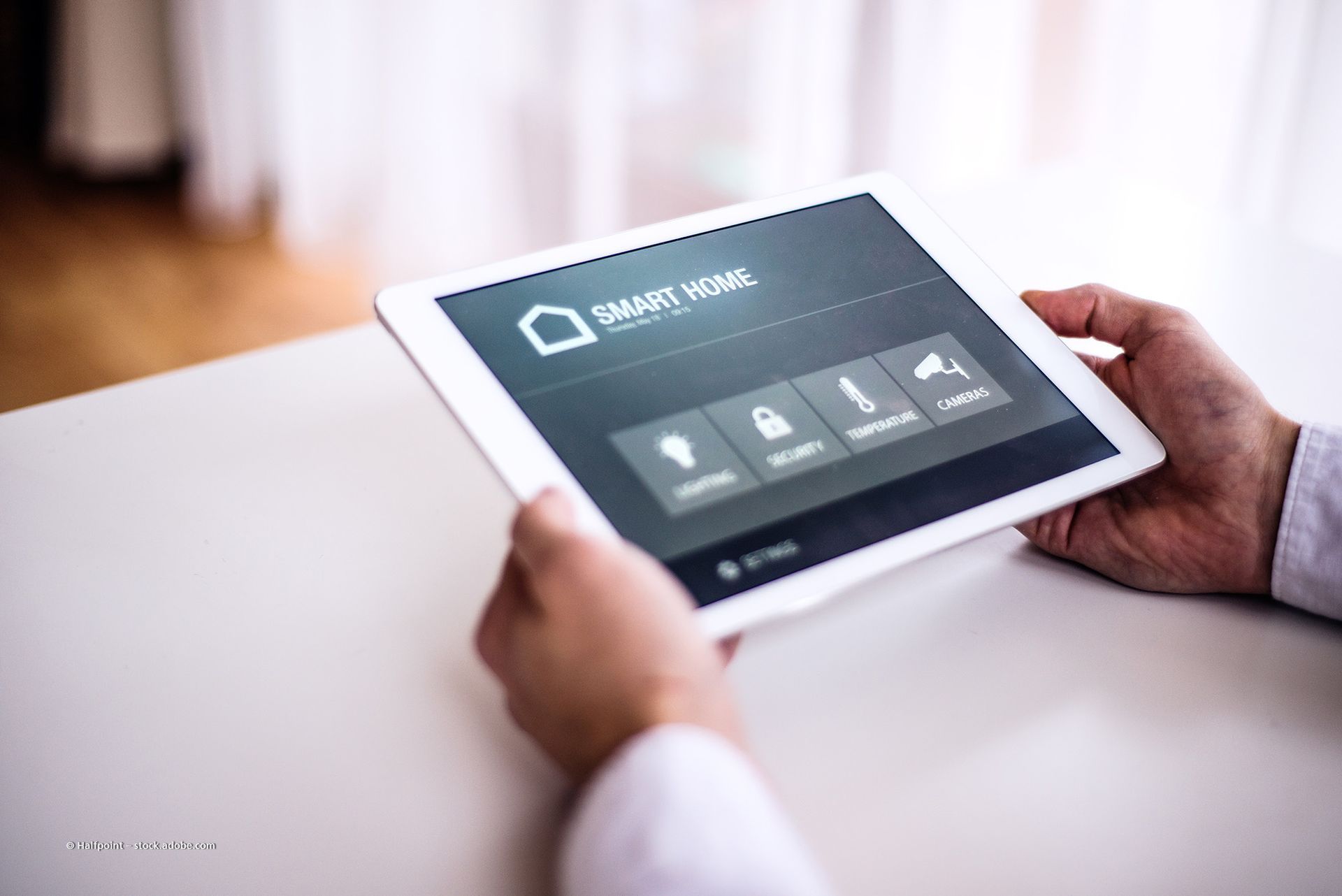 Eine Person nutzt ein Smartphone zur Steuerung von Smart-Home-Funktionen in einem modernen Wohnzimmer.