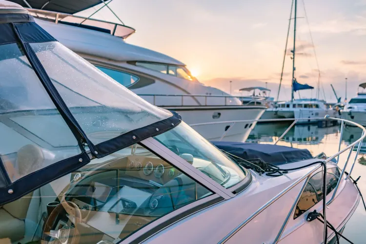 Barcos atracados en un puerto deportivo al atardecer; el cielo despejado se refleja en el agua.