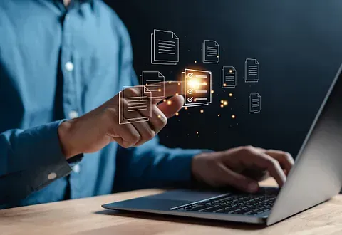 Hombre que usa un ordenador portátil, interactuando con documentos virtuales que flotan encima, lo que sugiere la gestión de documentos o el análisis de datos.