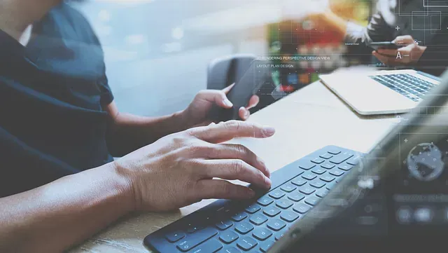 Persona que usa una tableta con teclado, sostiene un teléfono y trabaja en una computadora portátil, con gráficos de datos superpuestos.