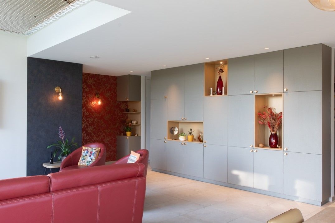Canapé rouge dans un salon moderne avec des meubles gris et des niches intégrées décorées.