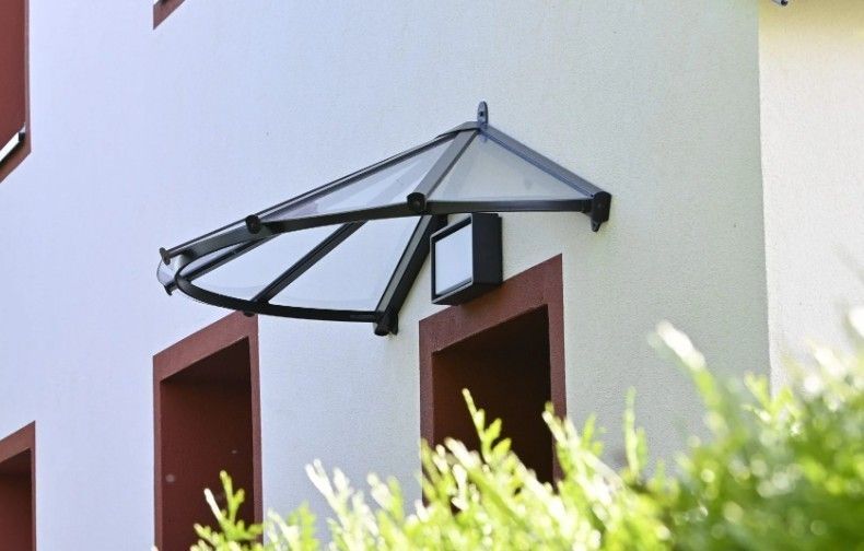 Un auvent en plastique noir et transparent au-dessus d'un luminaire extérieur.