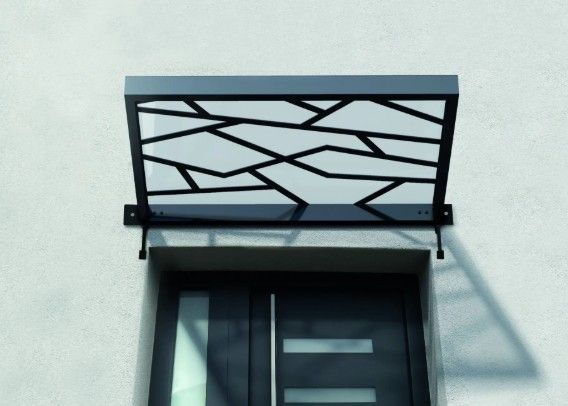 Auvent de porte en métal noir à motif géométrique au-dessus d'une porte.