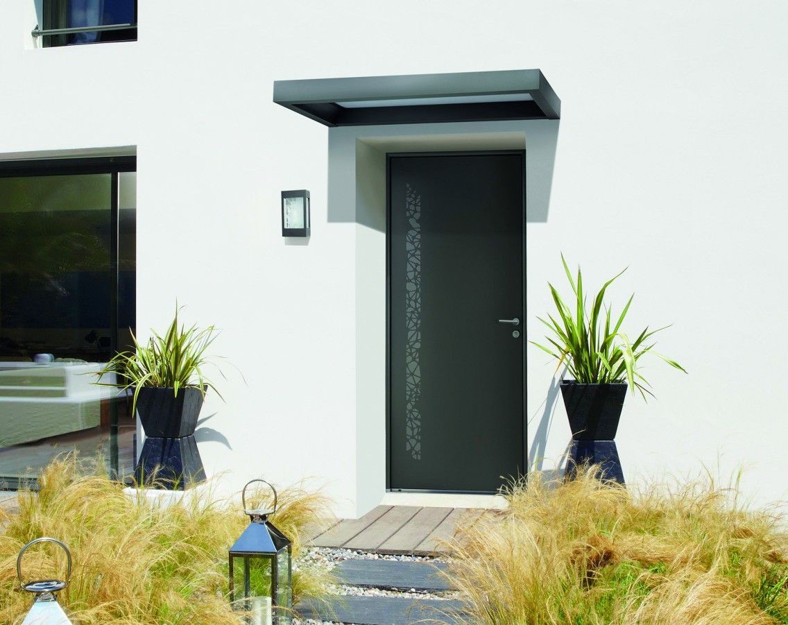 Porte d'entrée grise moderne avec petit auvent, flanquée de plantes en pot, sur une maison blanche.
