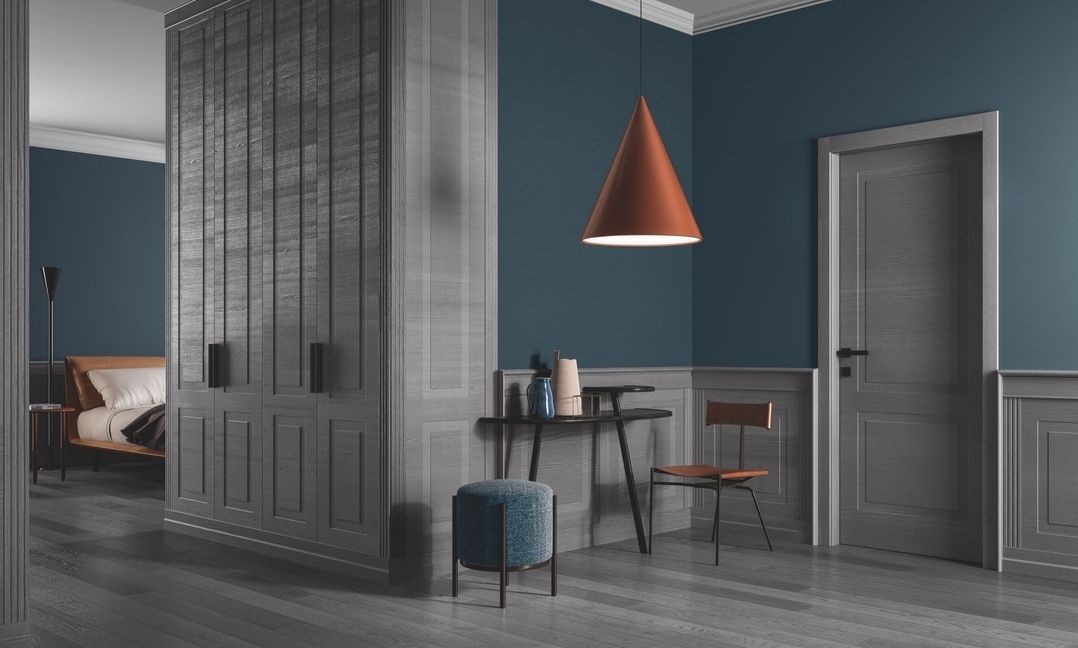 Murs et une armoire lambris gris, murs bleus, suspension lumineuse conique orange, petite table, chaise et pouf.