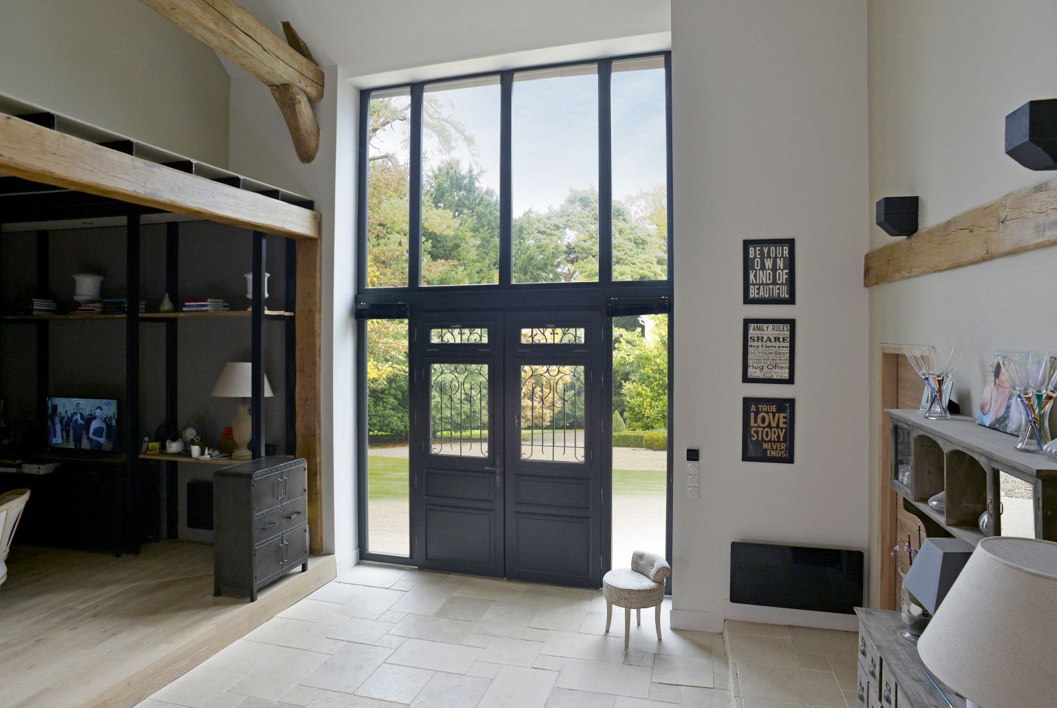 Grande pièce intérieure avec de hautes portes vitrées et une vue sur un jardin verdoyant luxuriant.