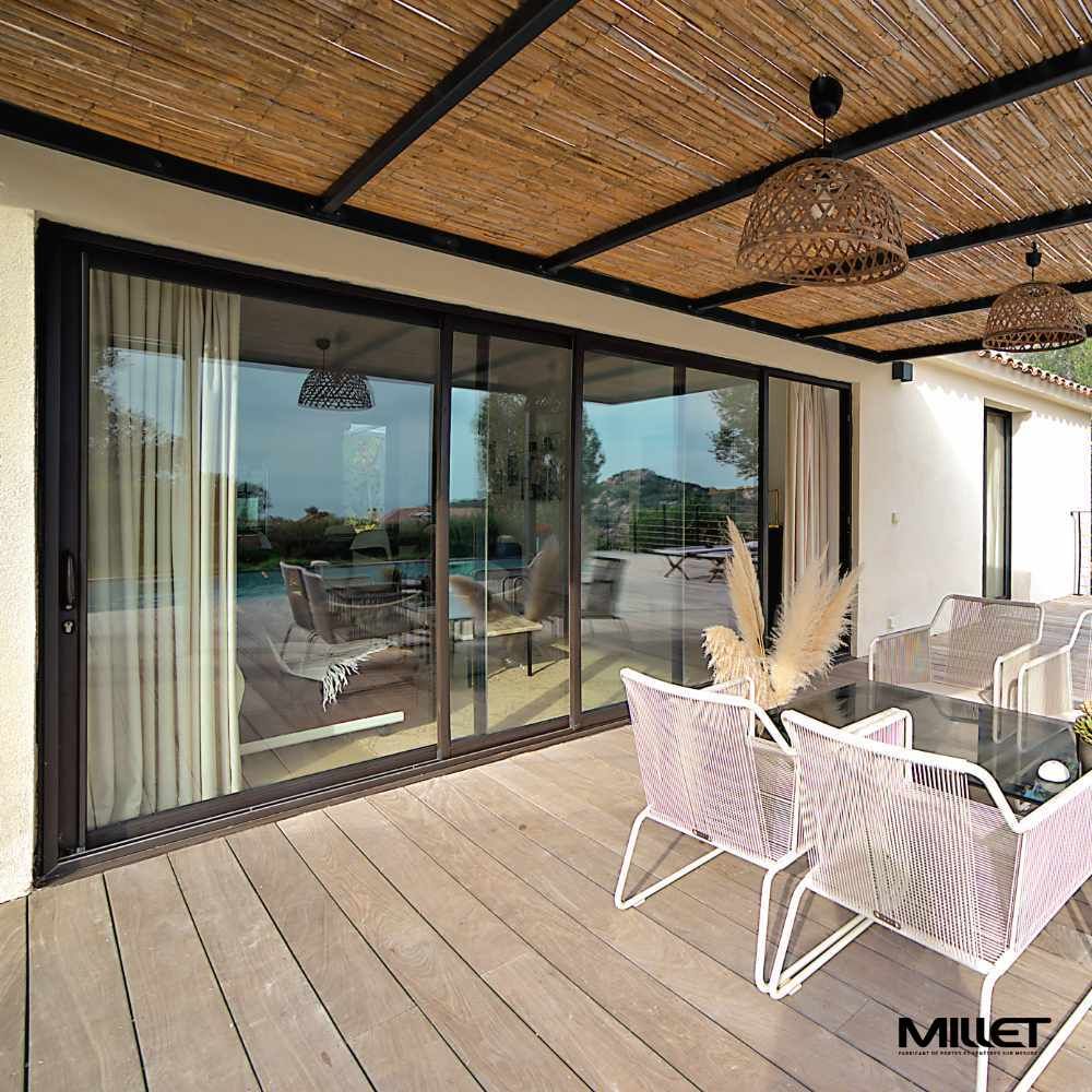 Grande baie coulissante noire qui donne sur une terrasse en bois