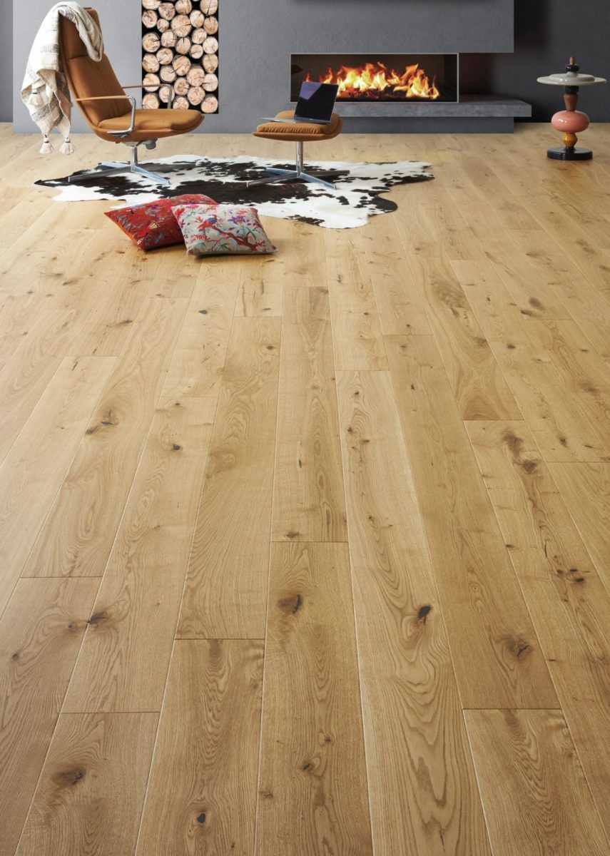 Parquet dans un salon avec cheminée, fauteuil en cuir, tapis et coussins.