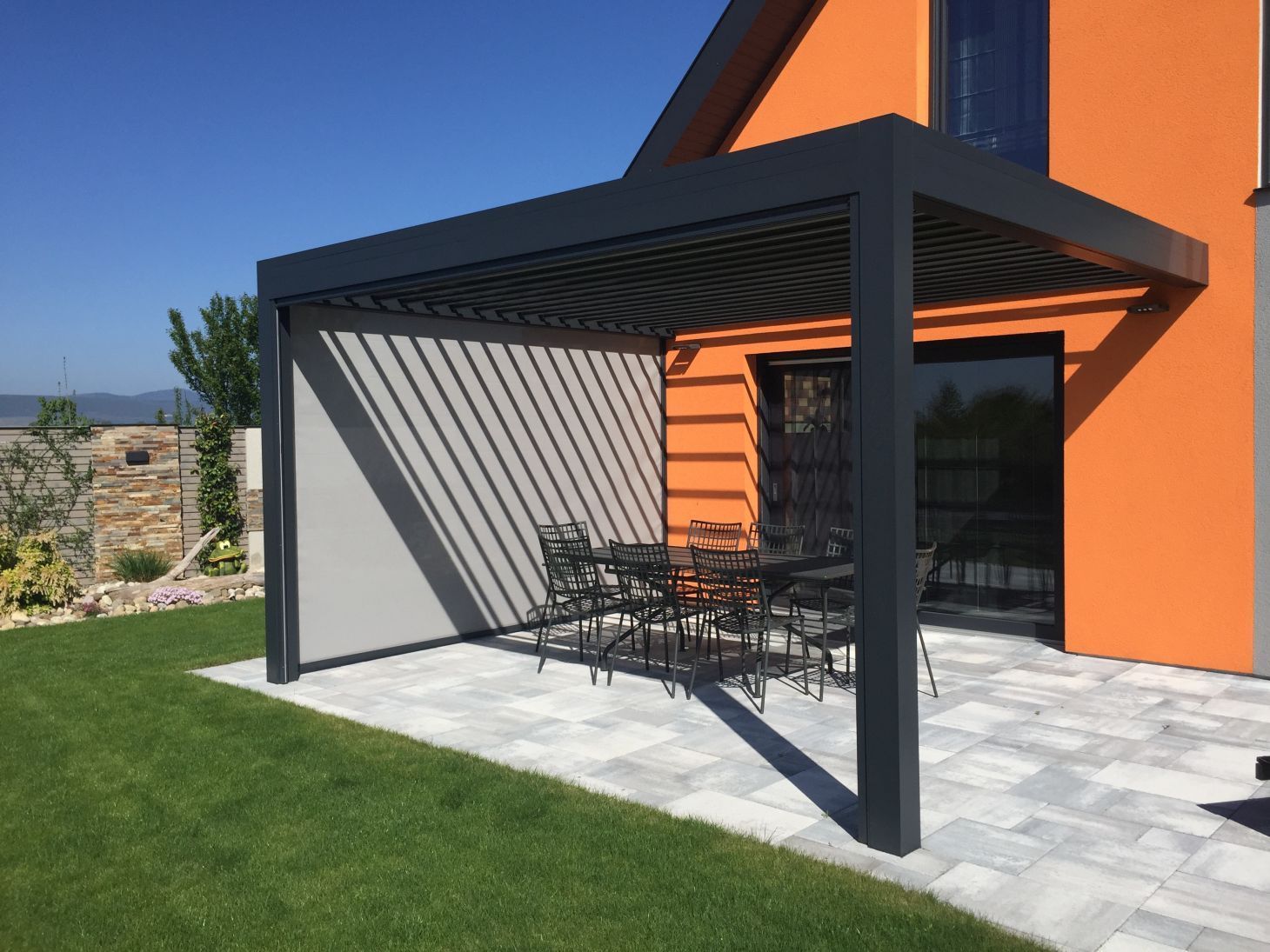 Maison orange avec une pergola noire sur la terrasse