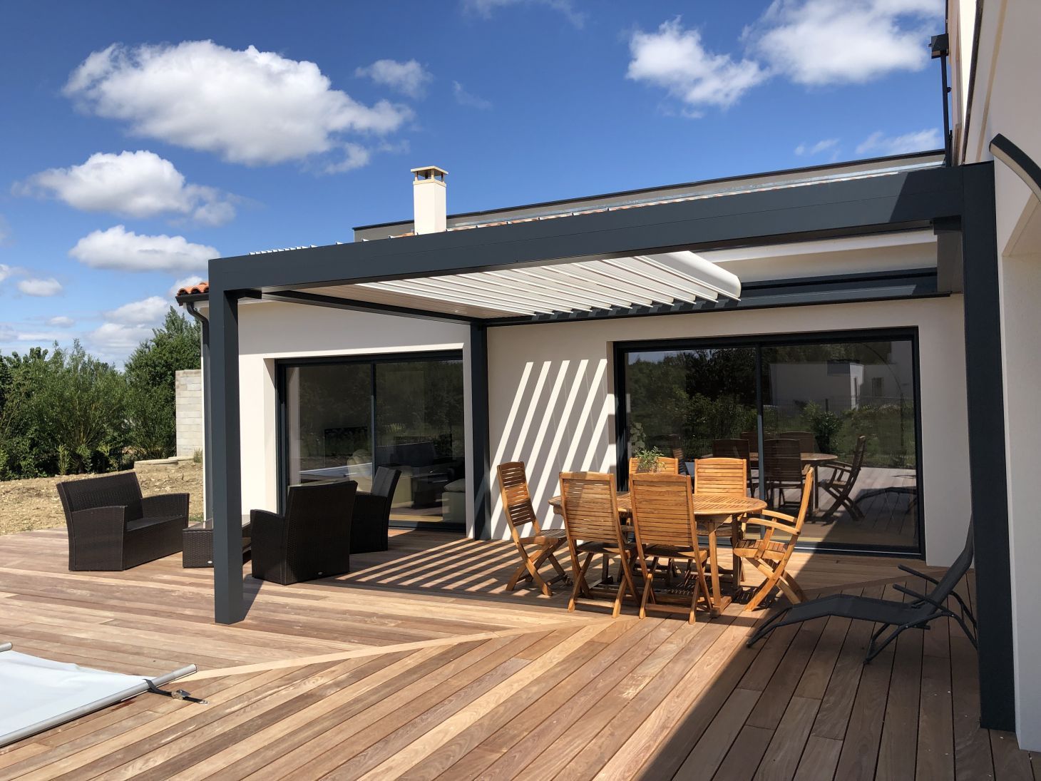 Pergola avec des lames rétractables sur une terrasse en bois