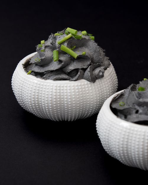 Dos cuencos blancos llenos de salsa negra y cebollas verdes.