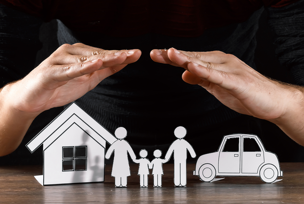 Una persona sta coprendo una casa, una famiglia e un'auto con le mani.