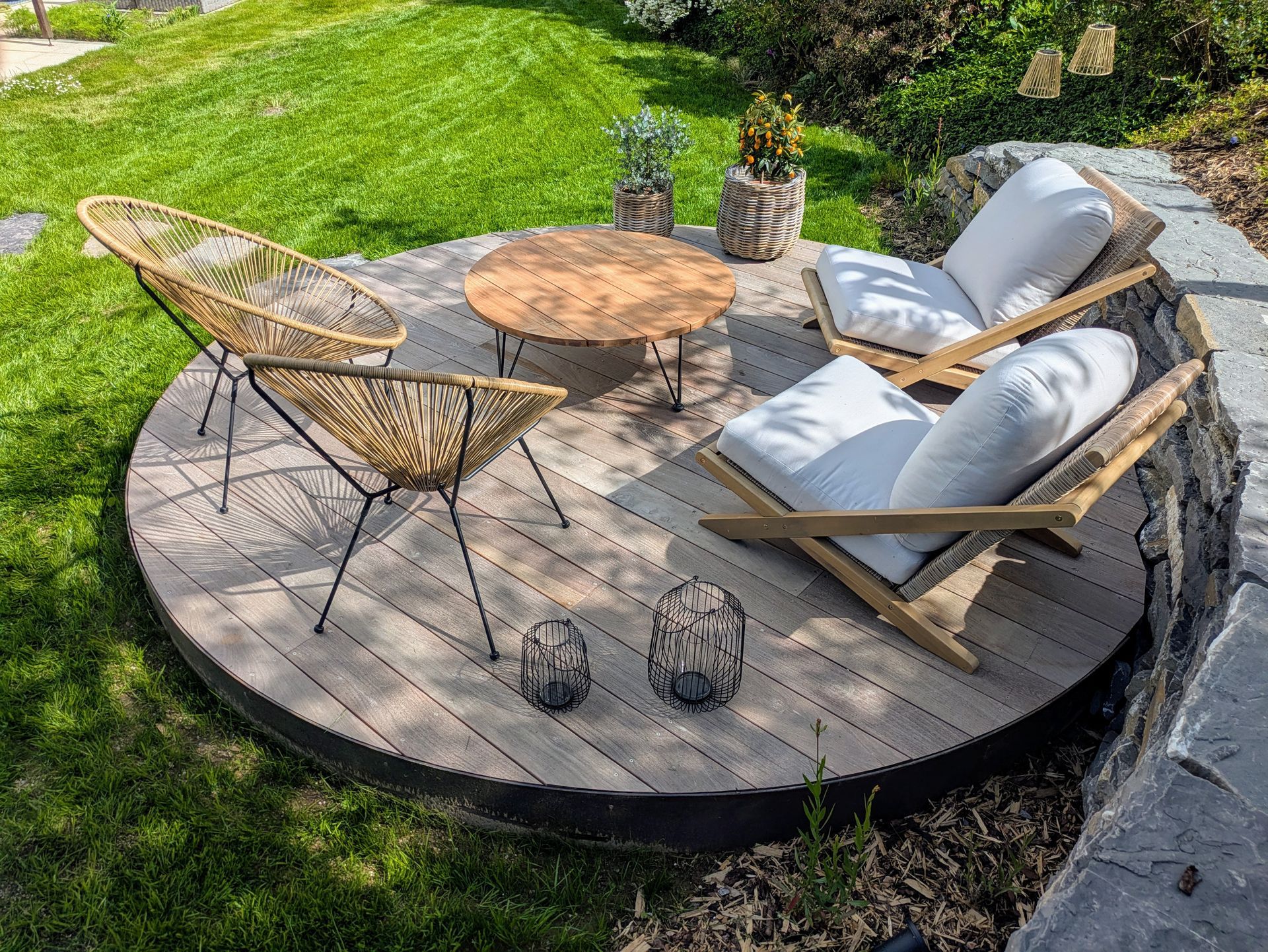 Un patio extérieur circulaire avec des sièges, une table et des plantes dans une zone herbeuse.
