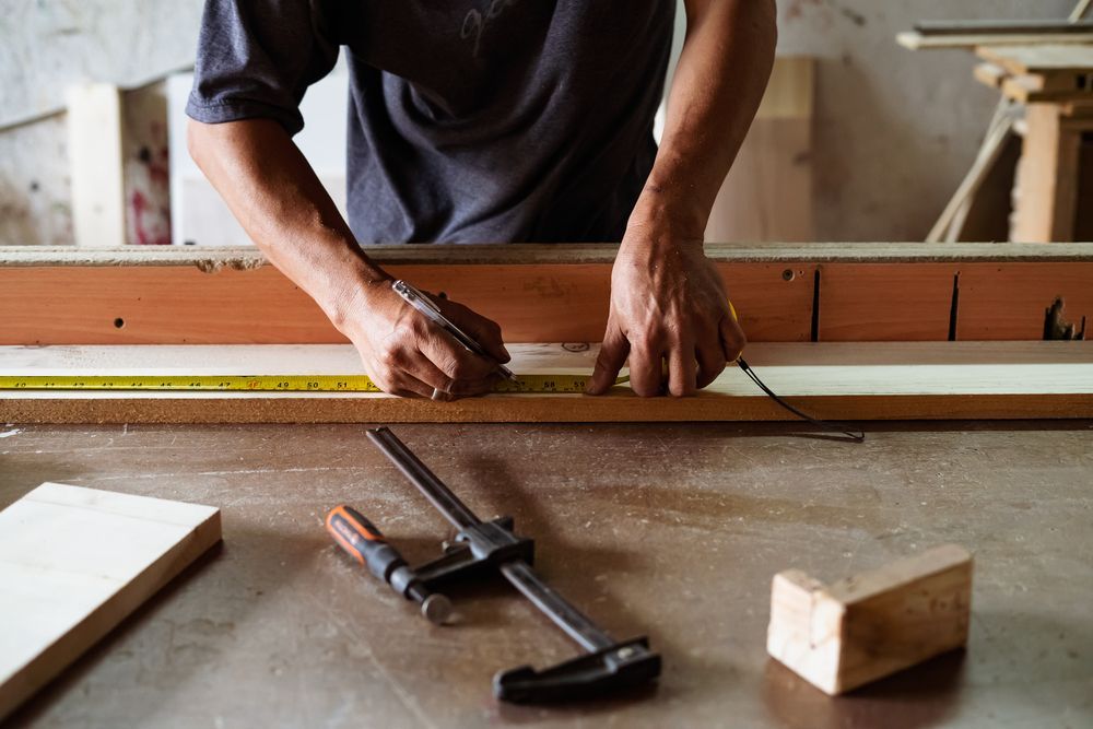 Un hombre está midiendo un trozo de madera con una cinta métrica.