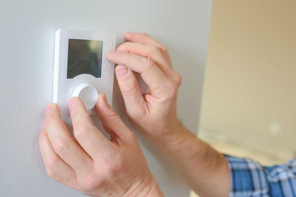 Una persona está ajustando un termostato en una pared.