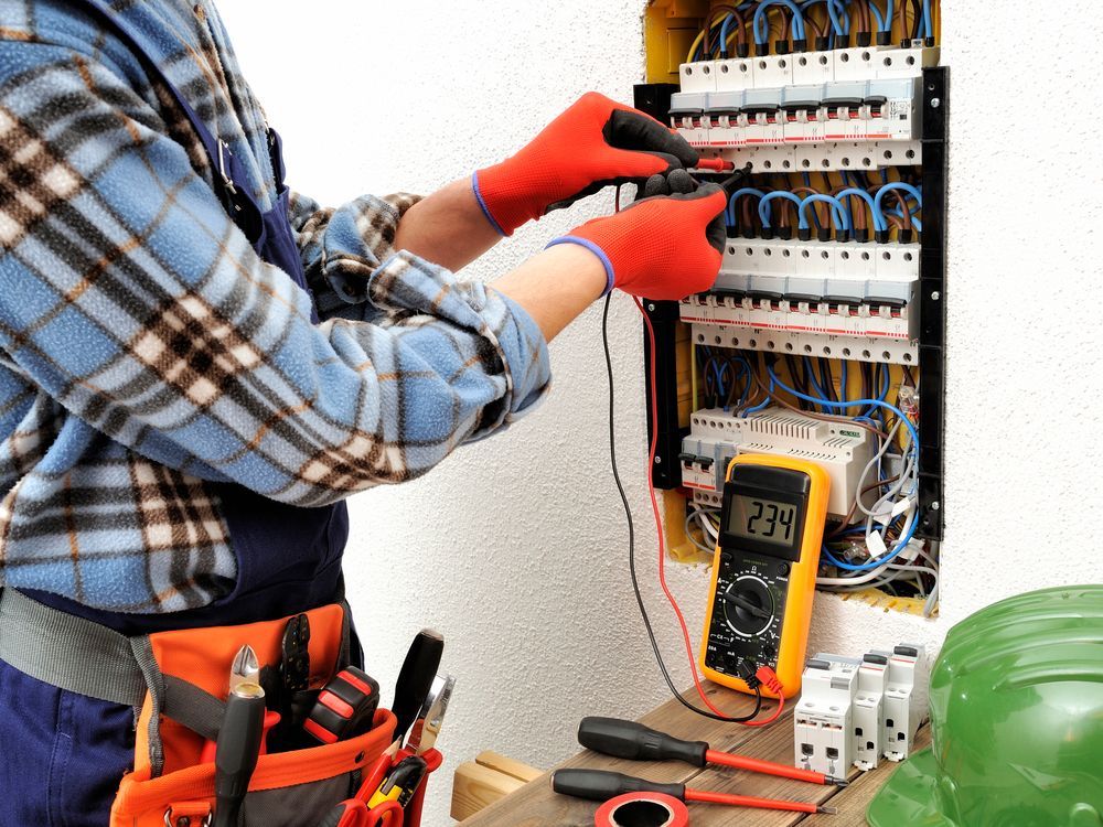 Un electricista está trabajando en una caja eléctrica con un multímetro.