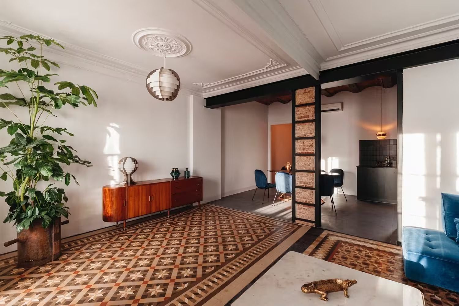 Una sala de estar con una alfombra, sillas, una mesa y una planta.