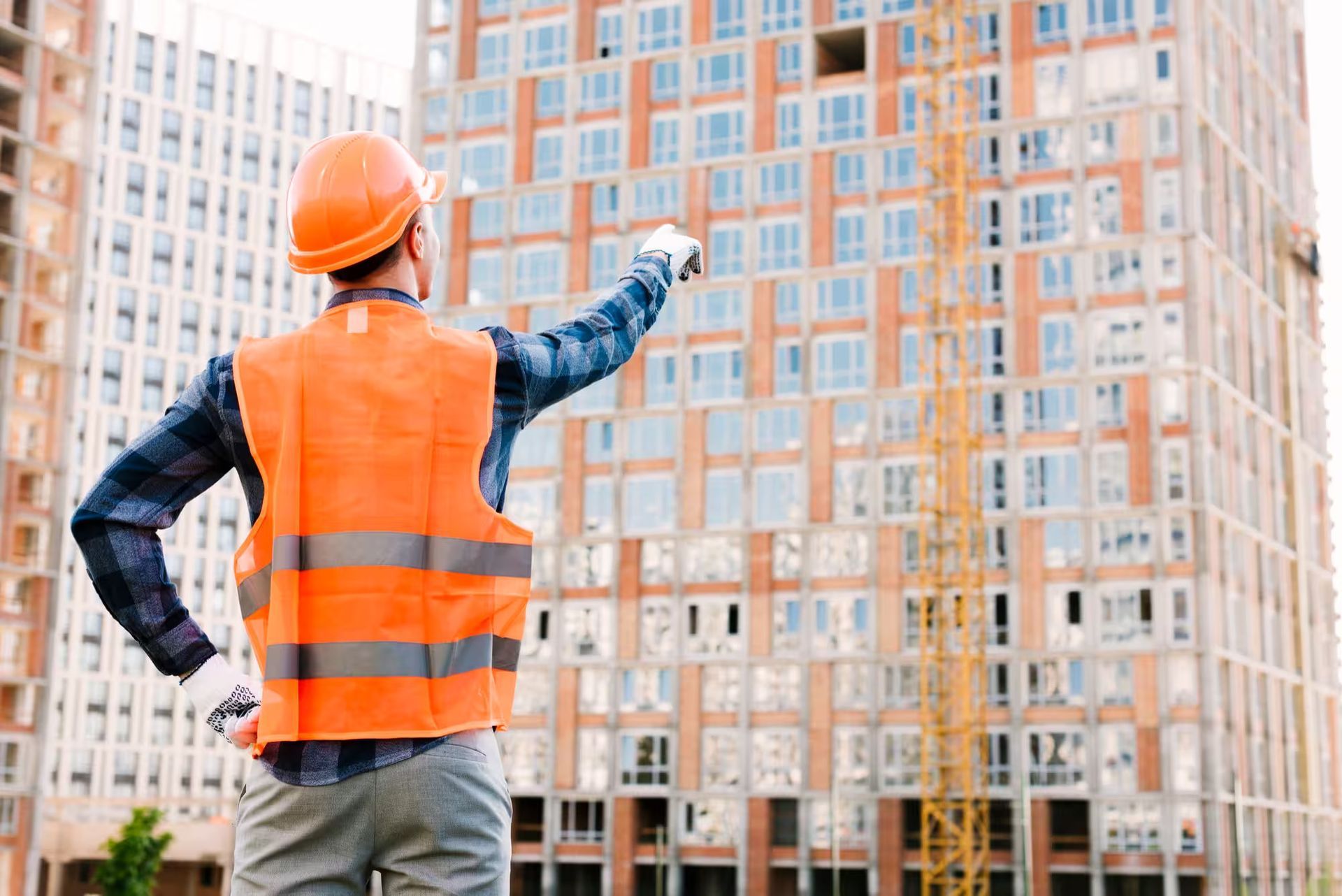 Un trabajador de la construcción está parado frente a un edificio en construcción.