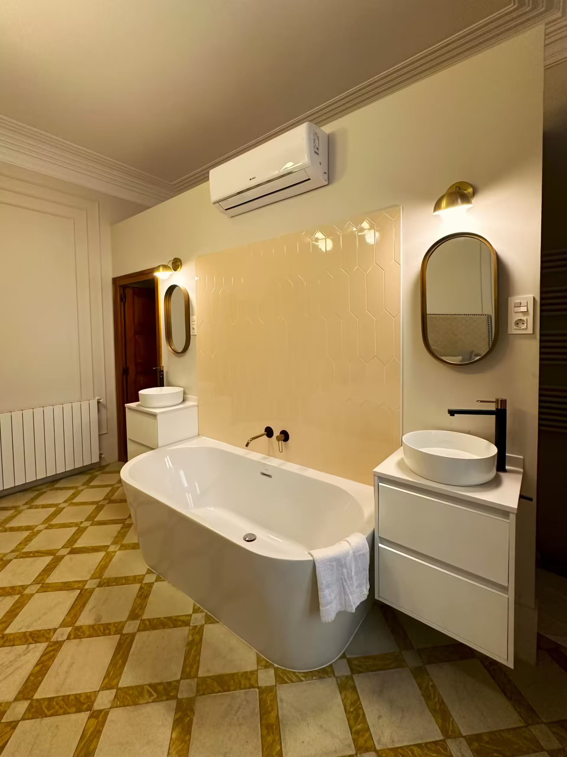 Un baño con bañera, lavabo, espejo y aire acondicionado.